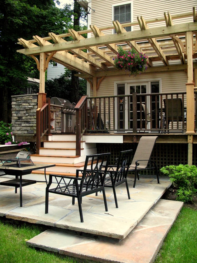 wood pergola covering the grill and outdoor seating on a backyard deck